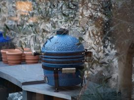 A blue grill on a table with terracotta pots in an outdoor area at Hilltop Cottage in Conwy