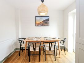 A dining area with a wooden table set for six with black chairs under a pendant light at The Hideaway Cromer in Northrepps near Overstrand