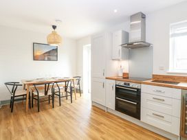A kitchen with wooden flooring and dining table with six chairs and an oven at The Hideaway Cromer in Northrepps near Overstrand
