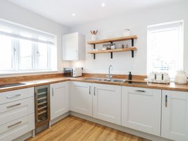 A kitchen with white cabinets wooden shelves and teak countertops at The Hideaway Cromer in Northrepps near Overstrand