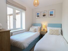 A bedroom with two single beds a wooden nightstand with a lamp and three pictures on the wall at The Hideaway Cromer in Northrepps near Overstrand