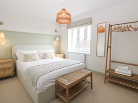 A bedroom with a double bed bedside tables a bench a clothes rack with hangers and towels and a window at The Hideaway Cromer in Northrepps near Overstrand