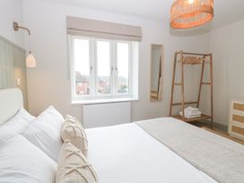 A bedroom with a bed pillows window wall mirror clothes rack and chest of drawers at The Hideaway Cromer in Northrepps near Overstrand