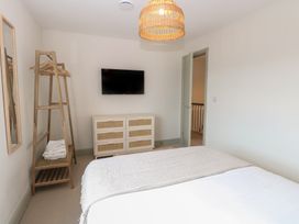 A bedroom with a bed a dresser a TV mounted on the wall a wooden clothes rack with hangers and towels at The Hideaway Cromer in Northrepps near Overstrand