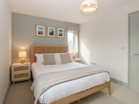 A bedroom with a wooden bed frame and beige pillows and blankets at The Hideaway Cromer in Northrepps near Overstrand