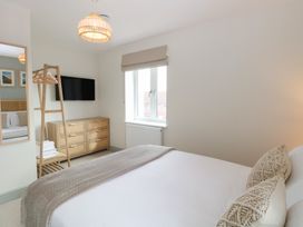 A bedroom with a bed pillows window dresser wall mirror and a television at The Hideaway Cromer in Northrepps near Overstrand