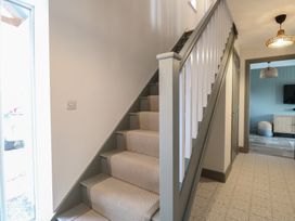 A stairway with carpet on the steps next to a window and a hallway leading to a room with a television at The Hideaway Cromer in Northrepps near Overstrand