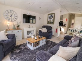 A living room with sofas a wall clock a coffee table and a TV at 98 The Heron in New Quay