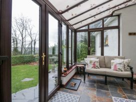A conservatory with a sofa and side table at Beech Brae in Kendal