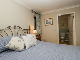 A bedroom with a bed and a door leading to a bathroom at Beech Brae in Kendal