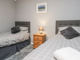 A bedroom with two beds and a lamp on a side table at Beech Brae in Kendal