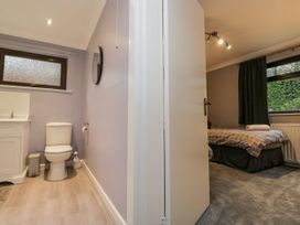 A bathroom with a toilet and sink adjoining a bedroom at Beech Brae Kendal