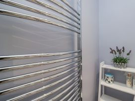 A towel radiator and shelf with decorative items at Beech Brae Kendal