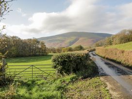 A scene depicting a gate and a winding road with mountains in the background at Beech Brae Kendal