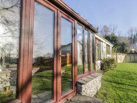 A conservatory with glass doors and a view of the garden at Beech Brae in Kendal