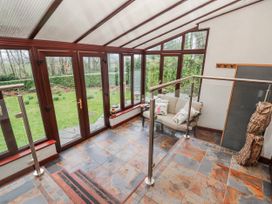 A conservatory with a sofa and glass doors at Beech Brae in Levens