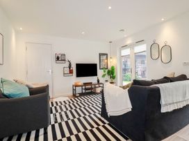 A living room with two sofas a striped rug a wall-mounted television and two mirrors at Treveglos in Porthtowan
