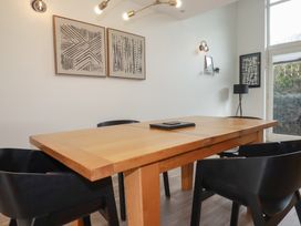 A dining room with a wooden table black chairs abstract wall art and a floor lamp at Treveglos in Porthtowan