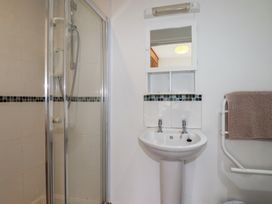 A bathroom with a shower enclosure a sink with two taps a mirror and a towel on a rack at Treveglos in Porthtowan