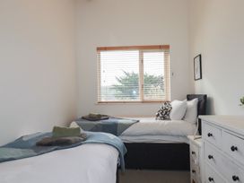 A bedroom with two beds a window with blinds and a white chest of drawers at Treveglos in Porthtowan