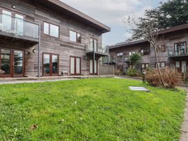 An outdoor area with green grass and wooden buildings with balconies at Treveglos in Porthtowan