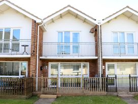 A two-story terraced house with balconies and wooden fences at No 108 Waterside in Corton