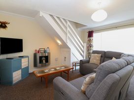 A living room with grey sofas wooden coffee table TV and console under stairs at No 108 Waterside in Corton