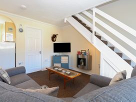 A living room with a sectional sofa a wooden coffee table a wall mounted TV and a staircase at No 108 Waterside in Corton