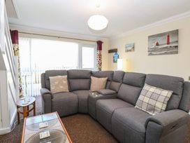 A living room with a gray sectional sofa and pillows a wooden coffee table and a side table near the stairs at No 108 Waterside in Corton