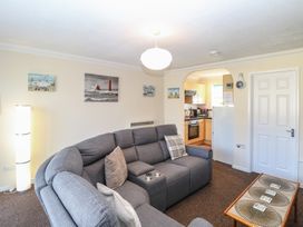 A living room with a gray sectional sofa and a coffee table near an archway to a kitchen at No 108 Waterside in Corton