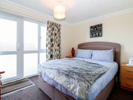 A bedroom with a double bed bedside tables and a window covered by patterned curtains at No 108 Waterside in Corton