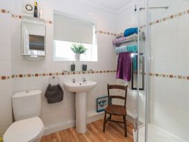 A bathroom with a toilet sink shower and wooden chair at No 108 Waterside in Corton