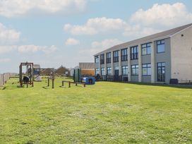 An outdoor playground with grass and play equipment next to a two story building at No 108 Waterside in Corton