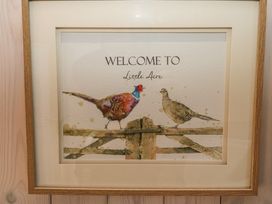 A framed picture of two birds on a wooden fence with the text welcome to Little Acre