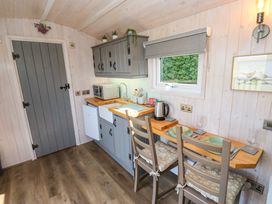 A kitchen with gray cabinets a wooden countertop dining table with place settings and two chairs at Little Acre in Oxenhope