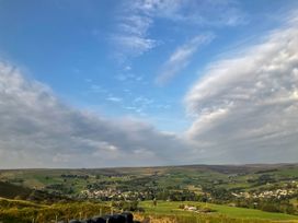 A rural landscape with green fields and scattered buildings under a blue sky at Little Acre in Oxenhope