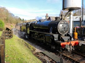 A steam locomotive on railway tracks next to a water tower at Little Acre in Oxenhope