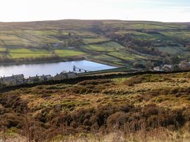 A hillside view overlooking a village with a reservoir and green fields at Little Acre in Oxenhope