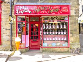 The exterior of Mrs Beightons Sweet Shop with red paint and jars of sweets in the window at Little Acre in Oxenhope