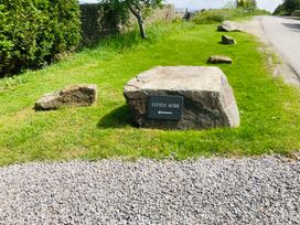 A sign for Little Acre with rocks and grass at Little Acre in Oxenhope