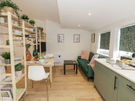 A living room with a dining area and kitchen appliances at Sea Pink Studio in Swanage