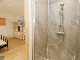 A bathroom with a shower and bed at Sea Pink Studio in Swanage