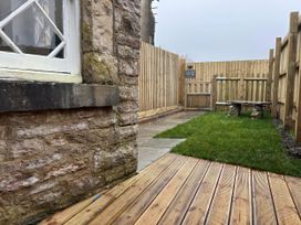 A garden with a stone wall and wooden bench at Sea Pink Studio in Langton Matravers