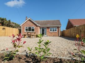 A single story brick house with a gravel yard and plants in front at The Hideaway in Bempton near Flamborough