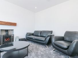 A living room with black leather sofa and armchair a round coffee table and a fireplace at The Hideaway in Bempton near Flamborough