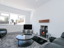 A living room with a fireplace television round coffee table and black chairs at The Hideaway in Bempton near Flamborough