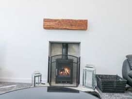A wood burning stove with fire inside on a carpeted floor with two lanterns and a wicker basket at The Hideaway in Bempton near Flamborough