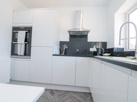 A kitchen with white cabinets a black countertop a double oven a stainless steel extractor hood and a faucet at The Hideaway in Bempton near Flamborough