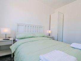 A bedroom with a bed with green bedding bedside tables with lamps and a tall mirror wardrobe at The Hideaway in Bempton near Flamborough