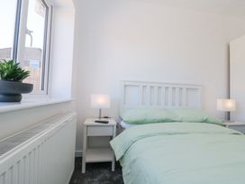 A bedroom with a bed green bedding two bedside tables with lamps and a plant on the window at The Hideaway in Bempton near Flamborough